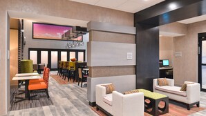 Un vestíbul modern amb zones d'estar, una pantalla de televisió gran i una escala.