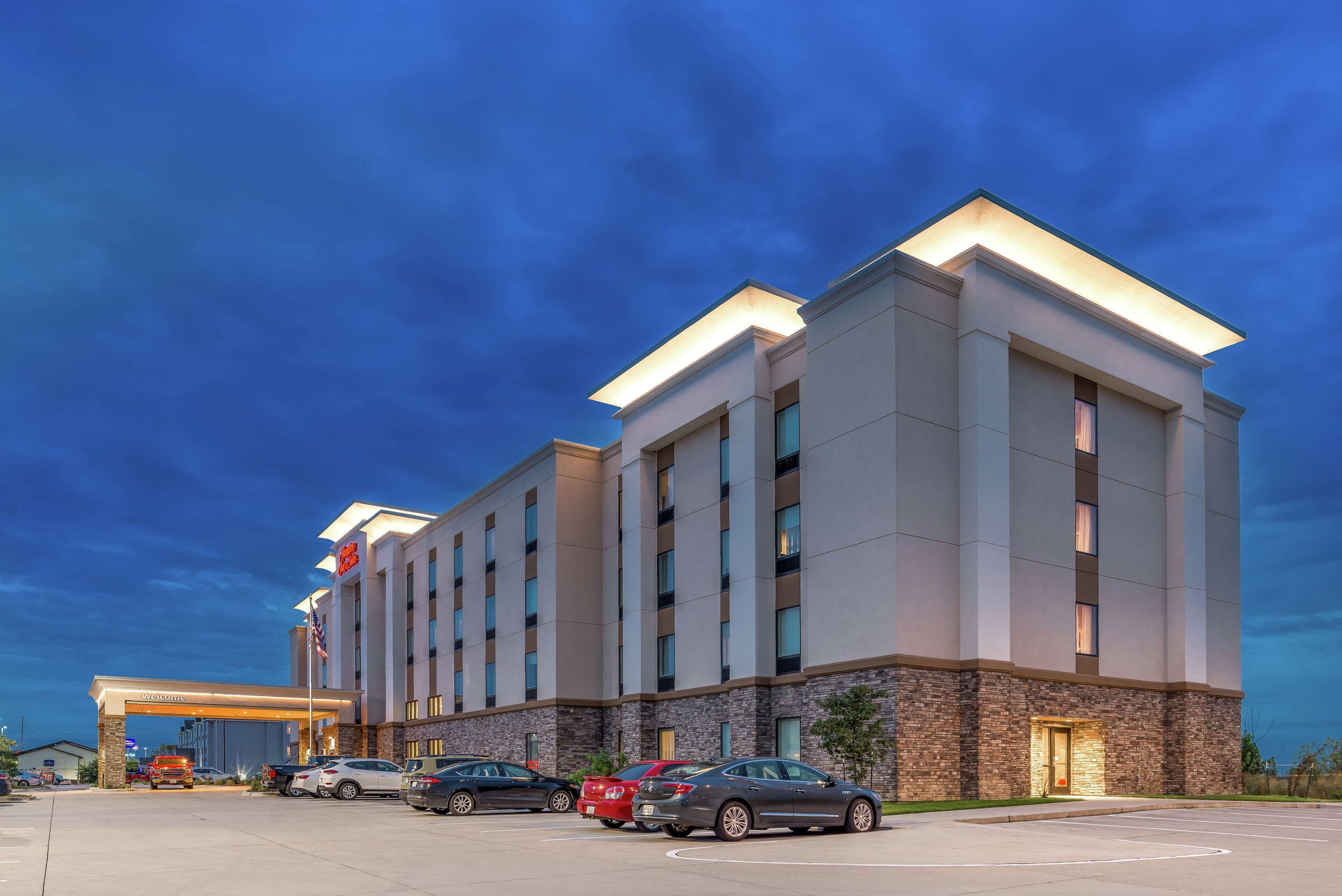 A modern hotel with a flat roof, a welcoming entrance, and a parking lot.