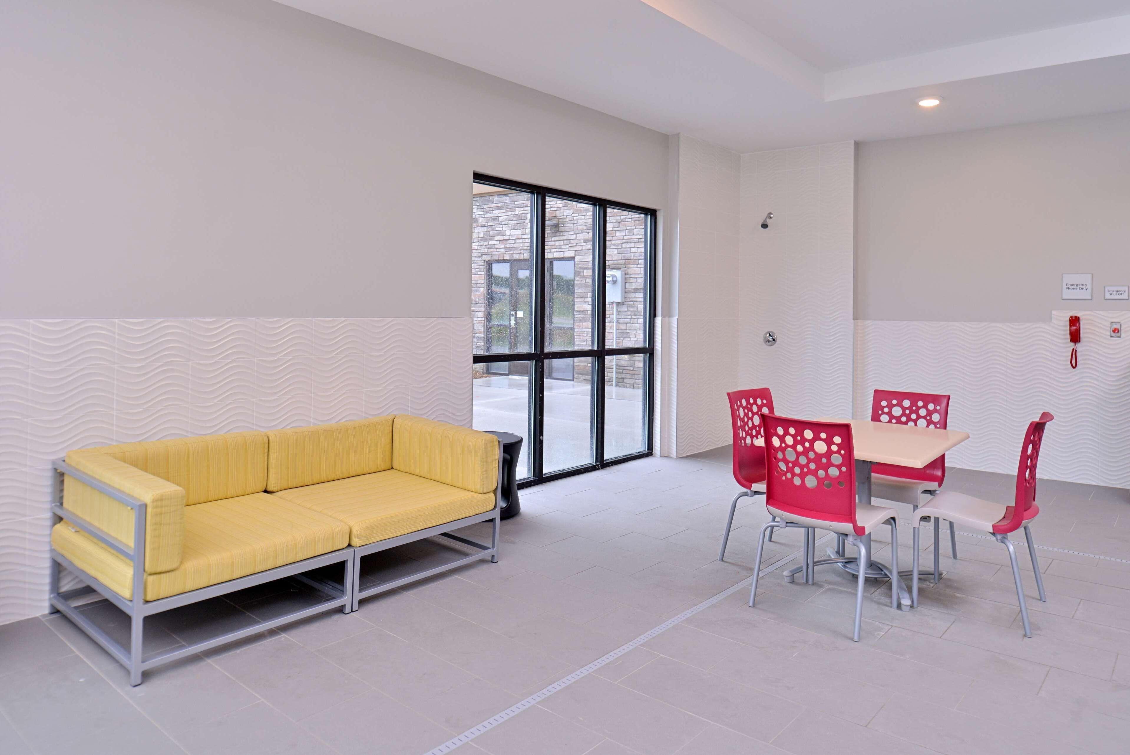 Una habitación moderna con un sofá amarillo, sillas rojas y una mesa.