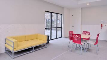 Una habitación moderna con un sofá amarillo, sillas rojas y una mesa.