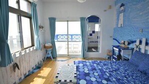 A bedroom with a bed, a window with curtains, a small table, and a view of the outside balcony. - Sea House homestay (Magong)