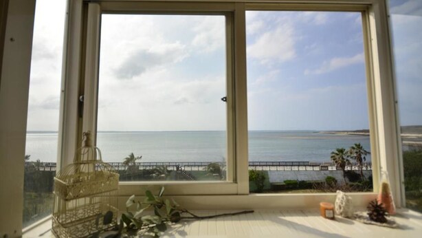 A room with a large window overlooking a beach and ocean. - Sea House homestay (Magong)