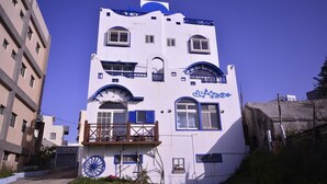 A multi-story building with a white facade and blue accents, featuring balconies and large windows. - Sea House homestay (Magong)