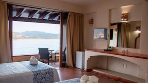 Habitación de hotel con dos camas, un escritorio, una silla, un televisor y vistas al mar.