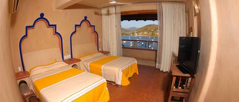 A hotel room with two beds, a TV, and a view of a body of water.