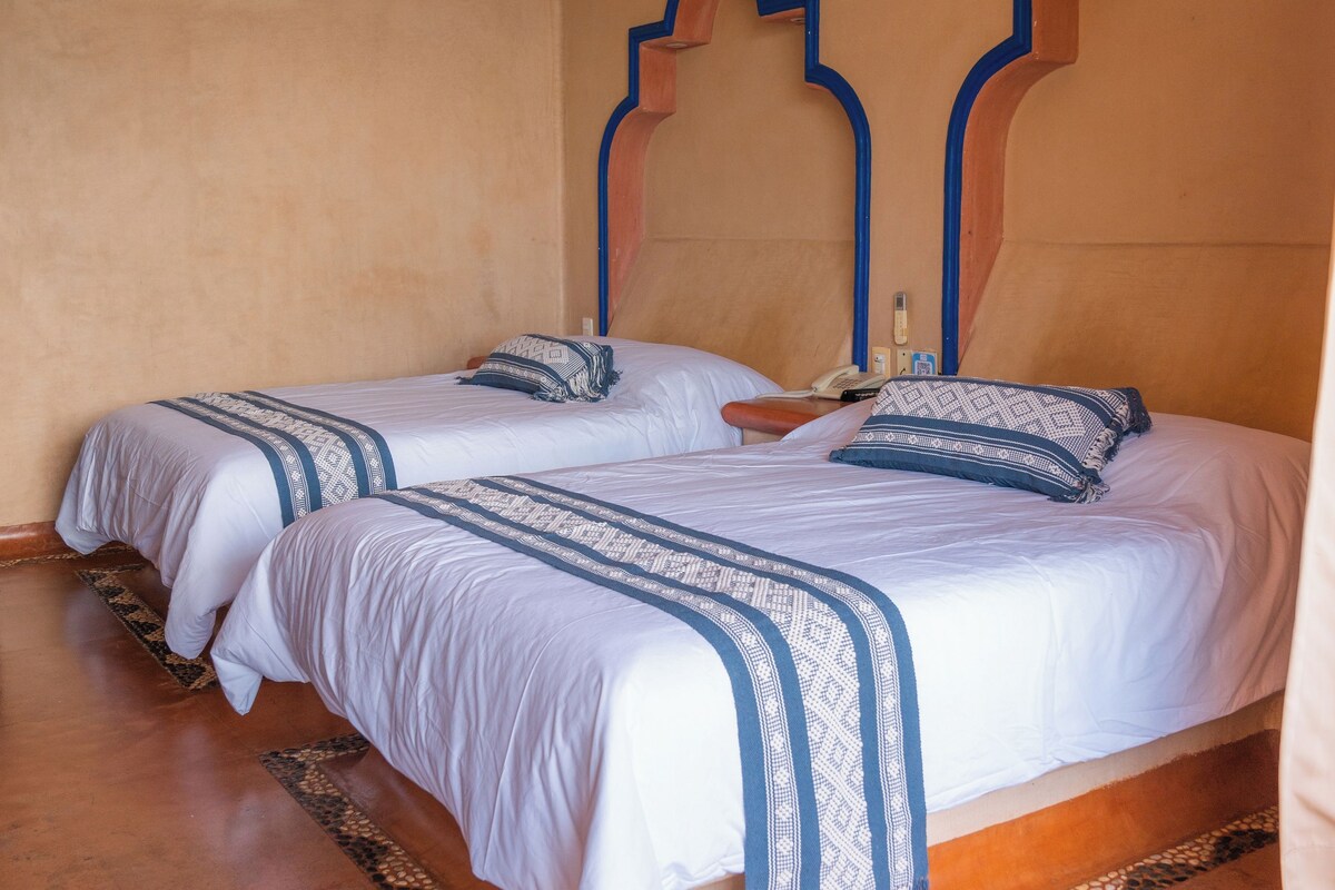 Una habitación con dos camas, ventilador de techo y aire acondicionado instalado en la pared.