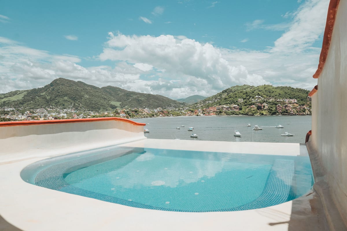 A swimming pool with a view of a lake and mountains.