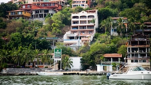 Una zona costera con un puerto deportivo, un barco blanco amarrado y un letrero de PEMEX.
