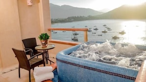 Un balcón con un jacuzzi, sillas, una mesa y una planta en maceta.