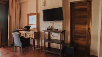 Una habitación con un escritorio de madera, una silla, un televisor montado en la pared y una puerta de madera.