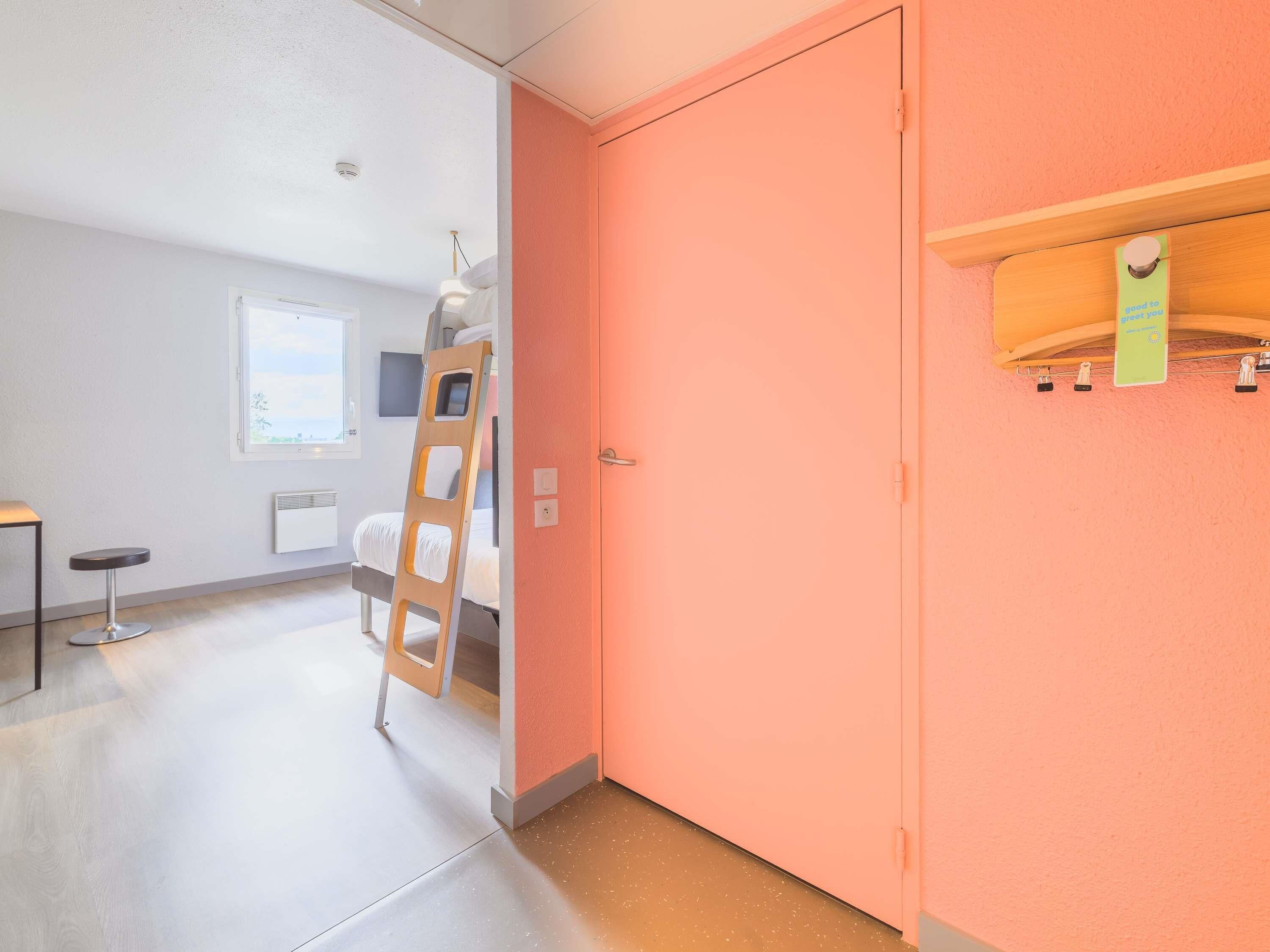 A room with a bunk bed, a ladder, a radiator, a window, and a door.