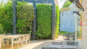 An outdoor patio with tables and chairs, a pergola with string lights, and a wall covered in climbing plants. - greet hotel Annecy Cran Gevrier (Annecy)