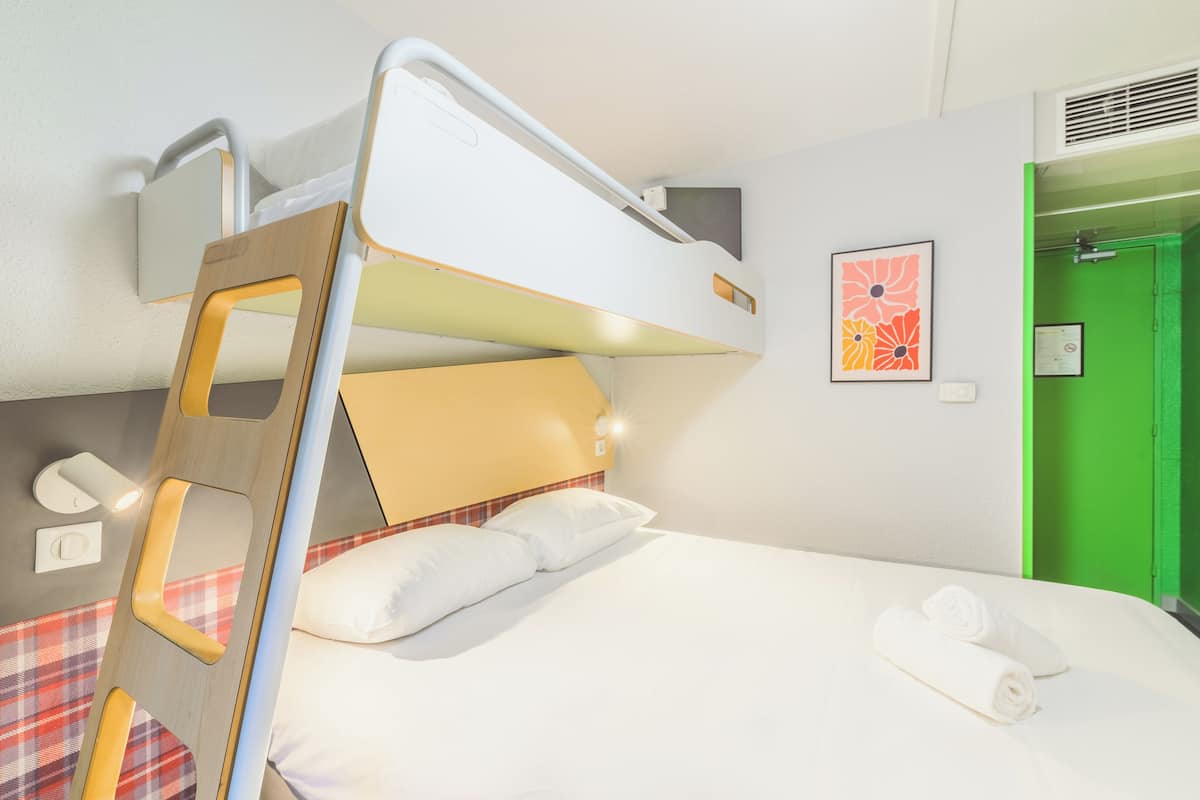 A bunk bed with a wooden ladder, white bedding, and a green door in the background.