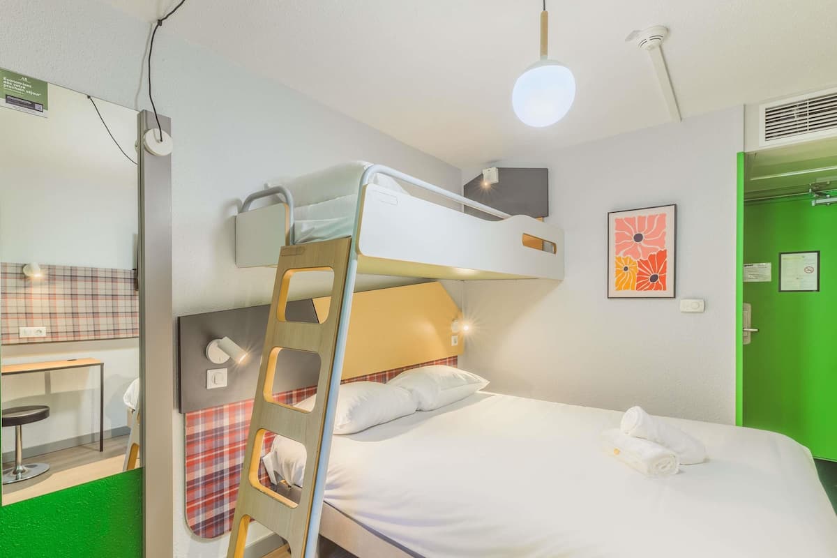 A bunk bed room with a ladder, a desk, and a green wall.