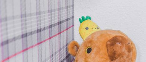 Un peluche con cabeza de piña y cuerpo marrón, situado junto a un tejido escocés con una franja roja.
