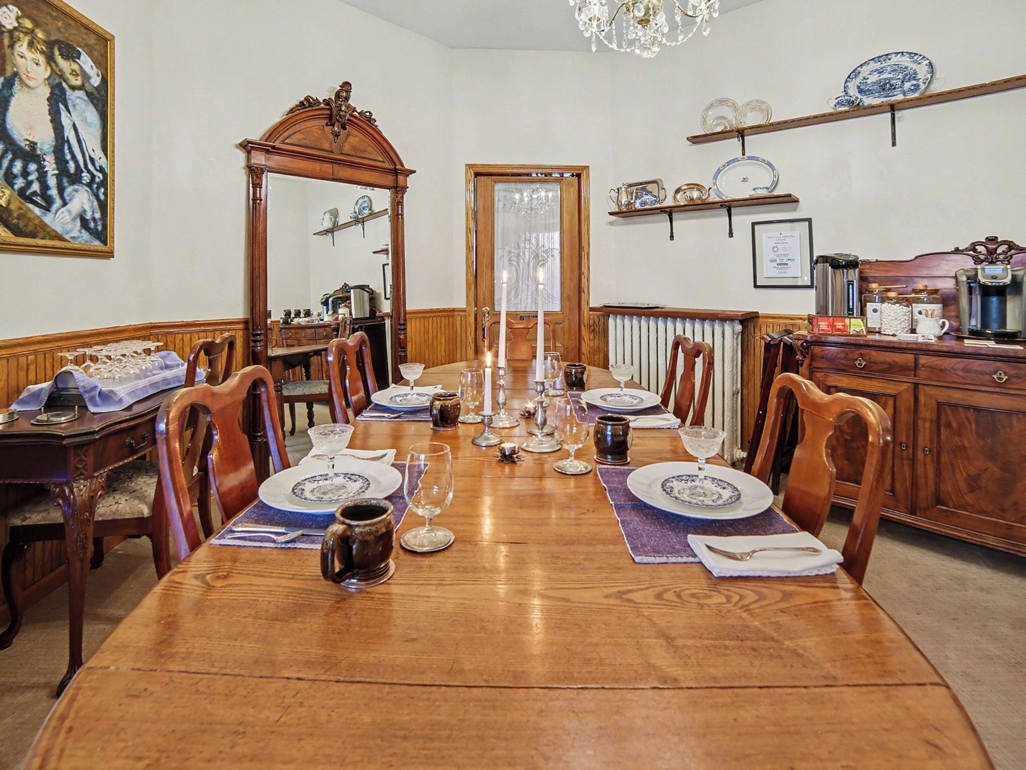 A dining room with a wooden table set for a meal, surrounded by chairs.