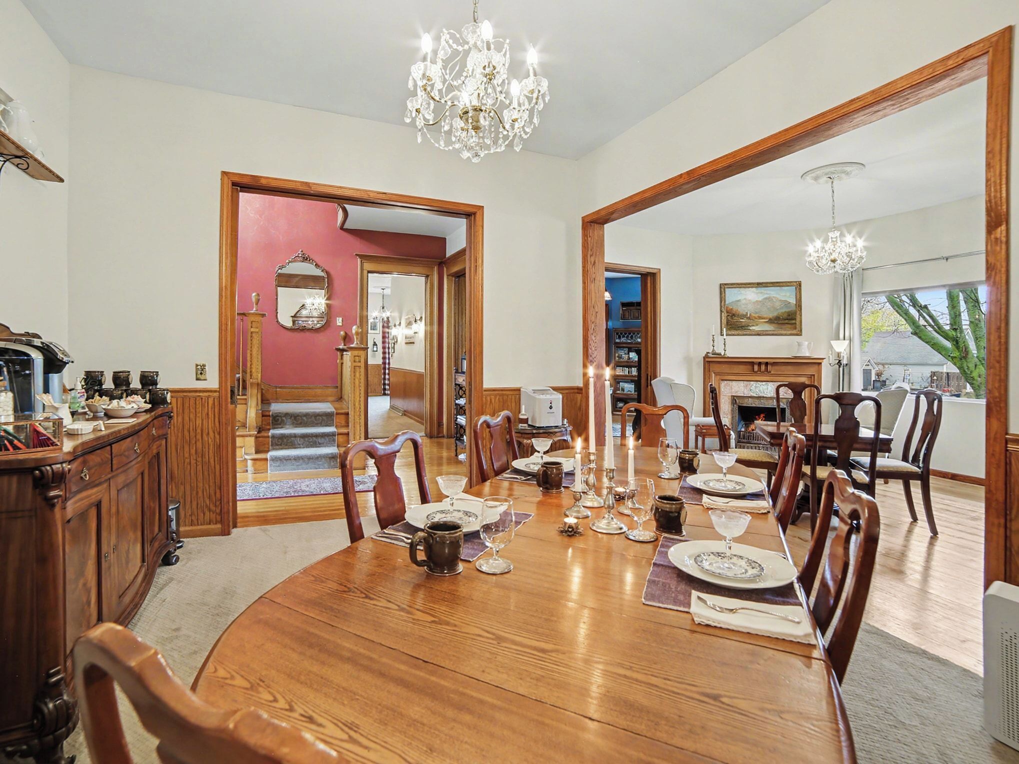 A dining room with a large wooden table set for a meal, surrounded by chairs.