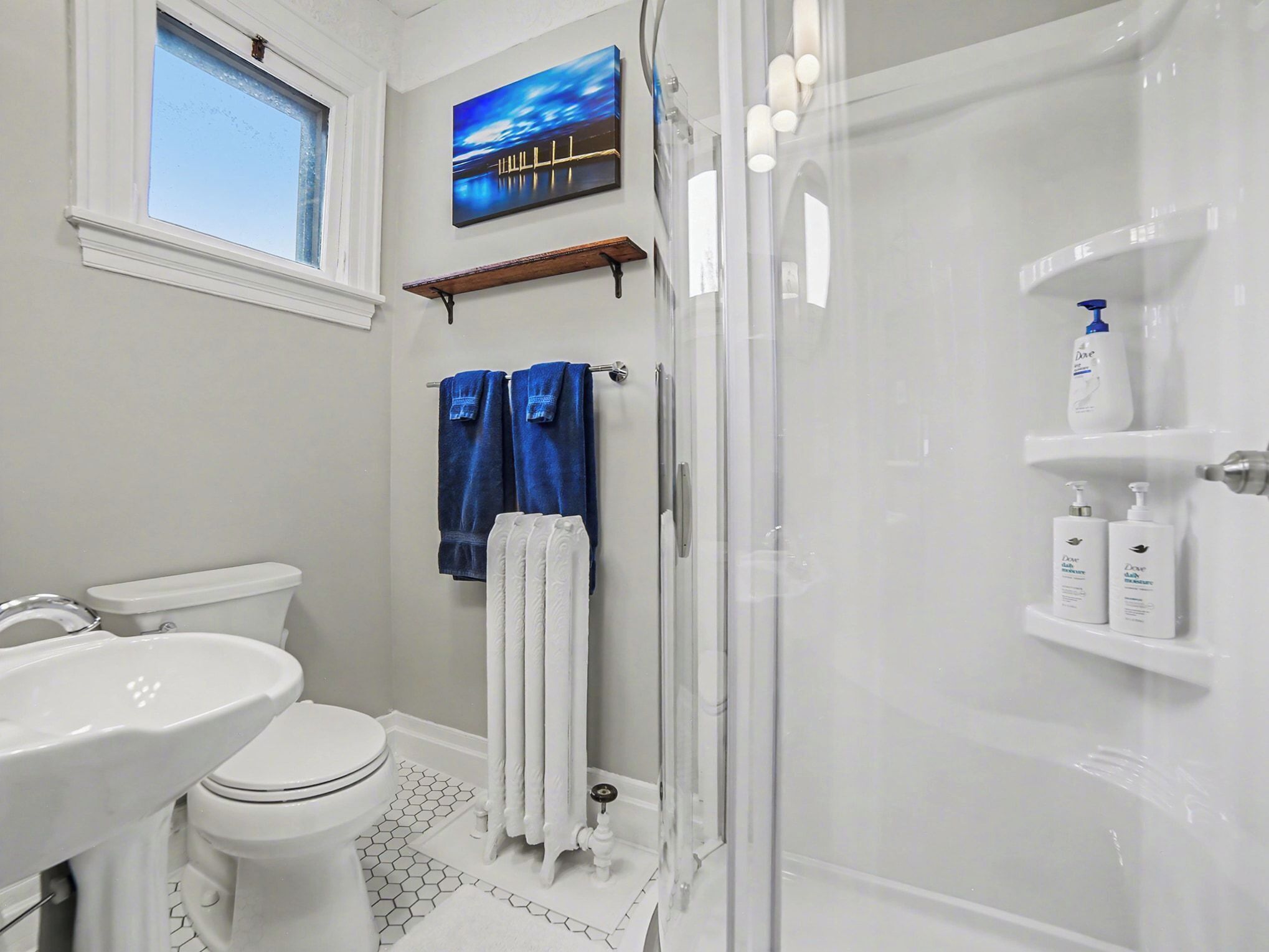 A bathroom with a toilet, sink, shower, and a glass-enclosed shower stall.
