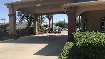 A building with a covered entrance and a parking lot.