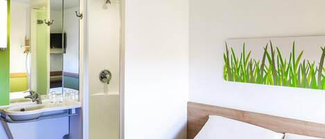 A hotel room with a bed, a bathroom with a sink, and a shower.