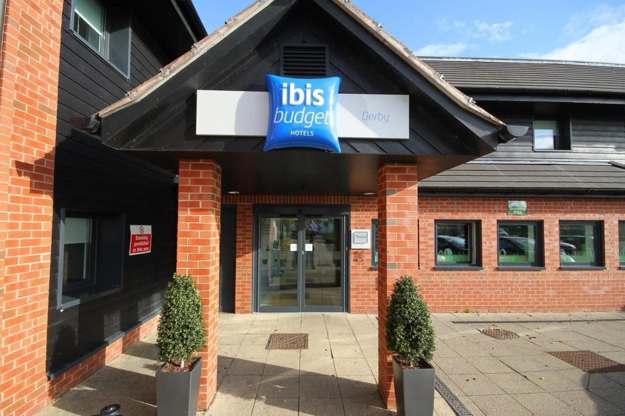 A hotel entrance with a sign for 'Ibis Budget Derby'.