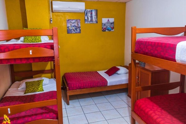 A dormitory room with bunk beds, a tiled floor, and wall art depicting cityscapes. - Flying Dog Hostels Iquitos (Iquitos)