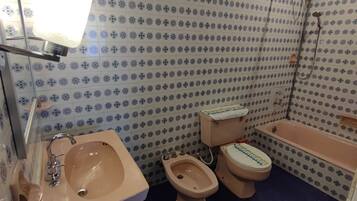 Un baño con lavamanos, bidé, inodoro y bañera, todos con un diseño de azulejos de motivos florales.