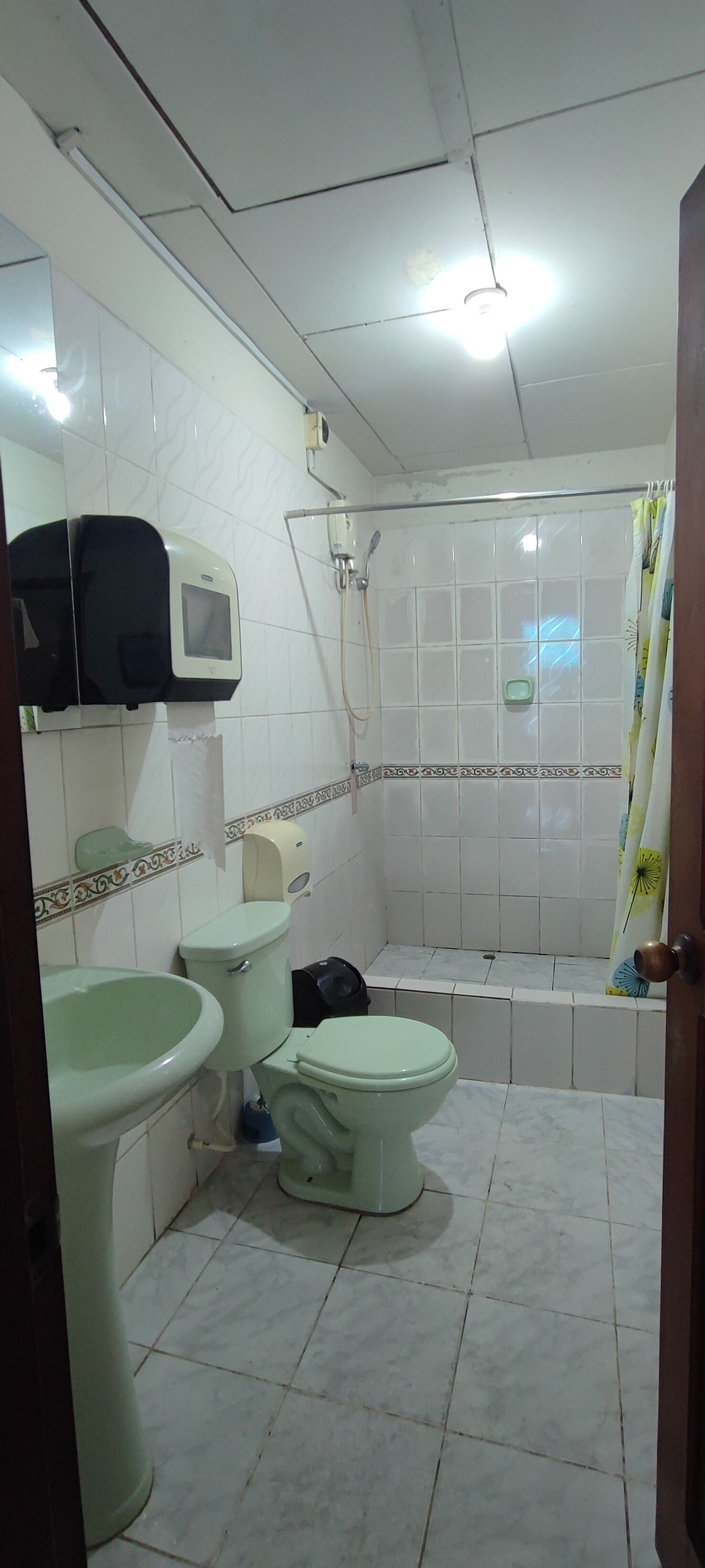 Une salle de bain avec deux toilettes, un lavabo, une douche et un porte-rouleau de papier toilette.