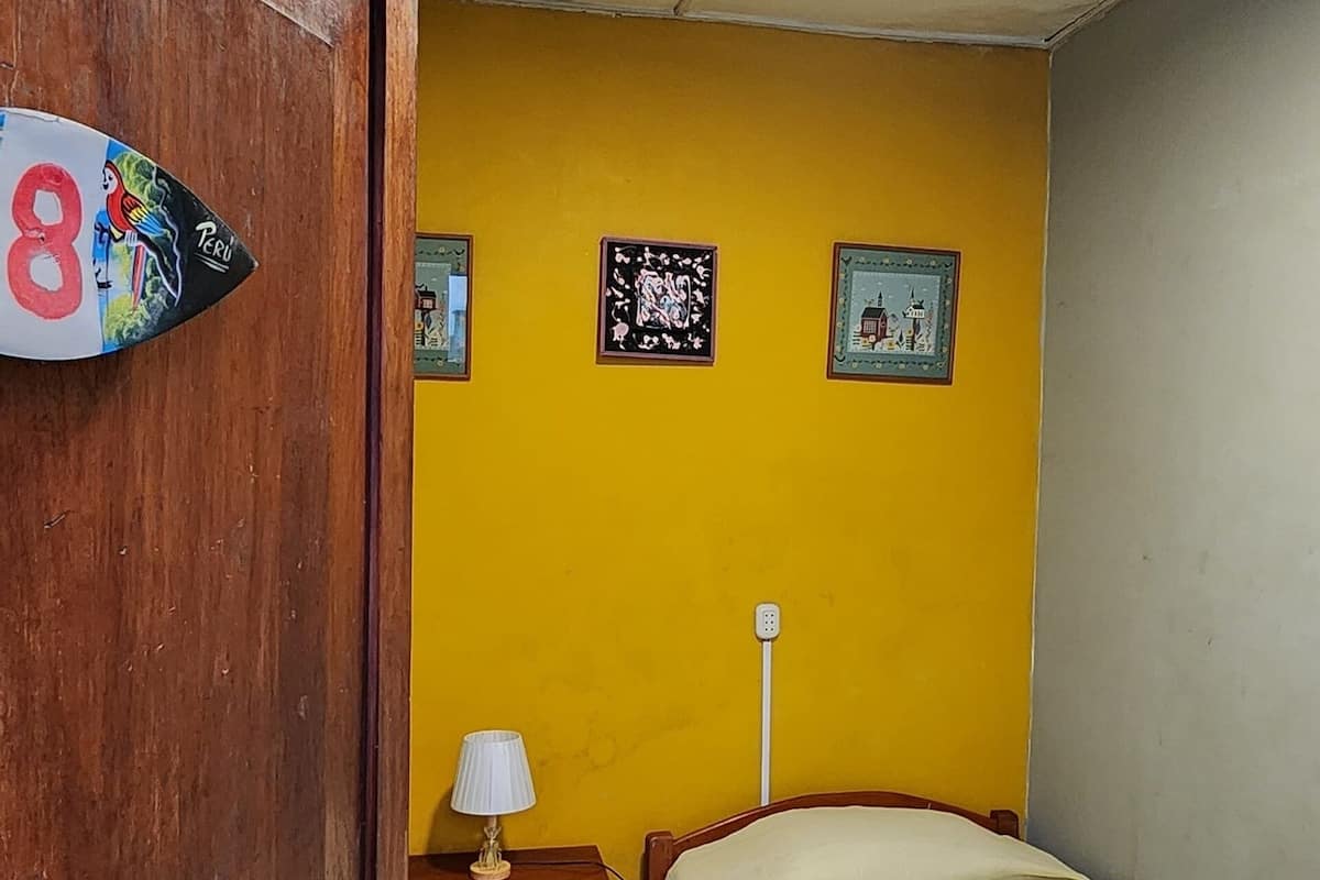 A room with a bed, a nightstand, a lamp, and a wall with three framed pictures.