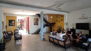 A spacious living area with a staircase, a sofa, and a television. - Flying Dog Hostels Iquitos (Iquitos)