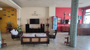 A living room with a sofa, chairs, a TV, a bookshelf, and a staircase. - Flying Dog Hostels Iquitos (Iquitos)