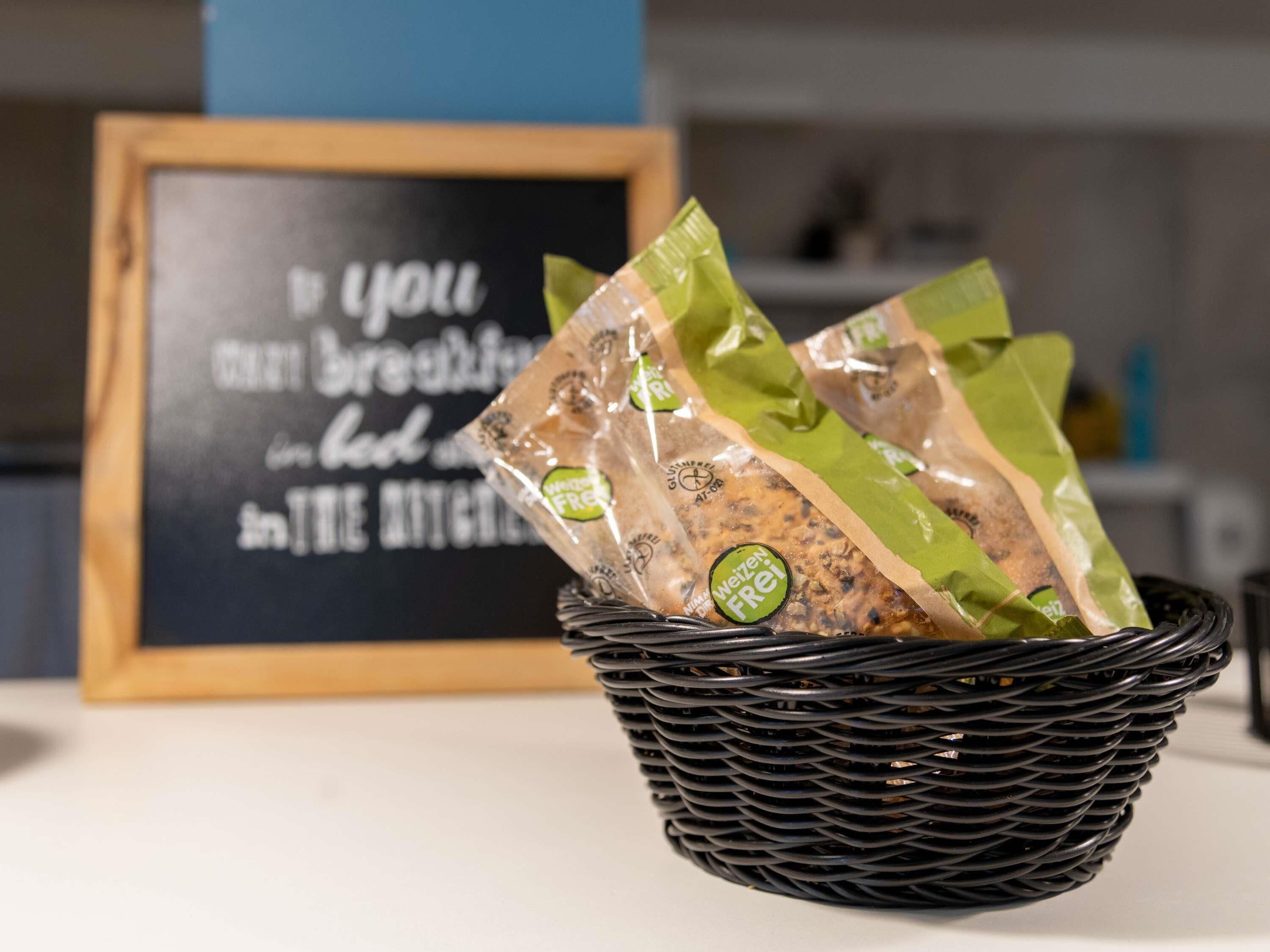 A black woven basket filled with green and brown packaged food items on a table.