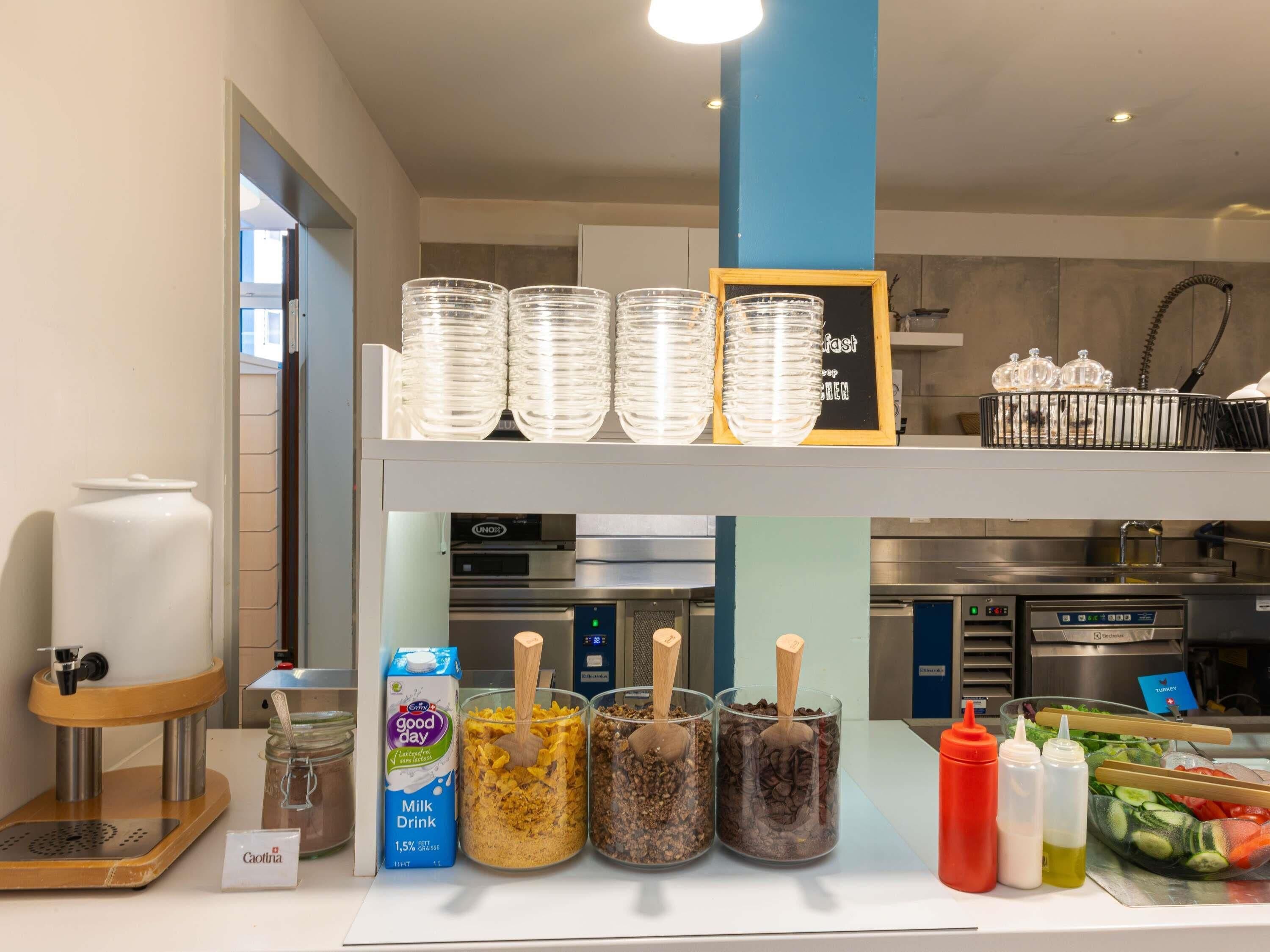 Un buffet pour le petit-déjeuner comprenant une machine à café, des boissons lactées, des condiments et un assortiment de salades.