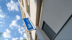 Un edificio con un letrero azul que dice "Ibis budget" y una ventana con una reja de metal.