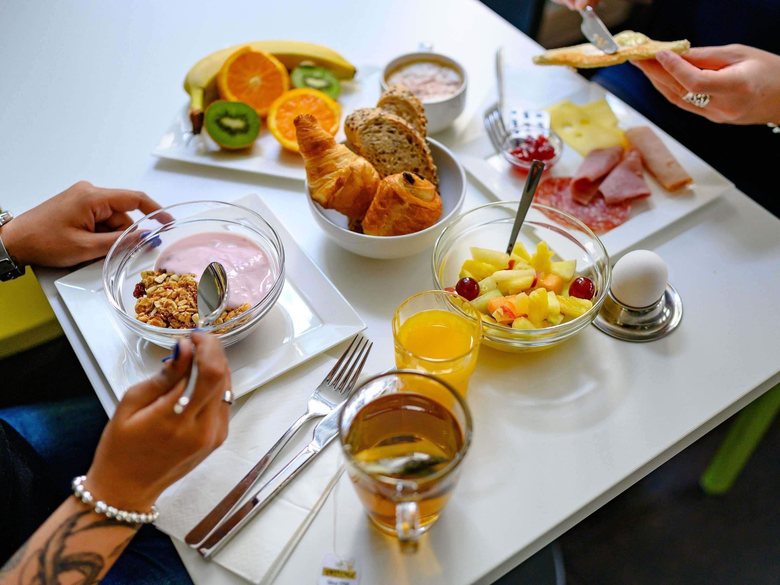 A breakfast setting with various food items and utensils on a table.