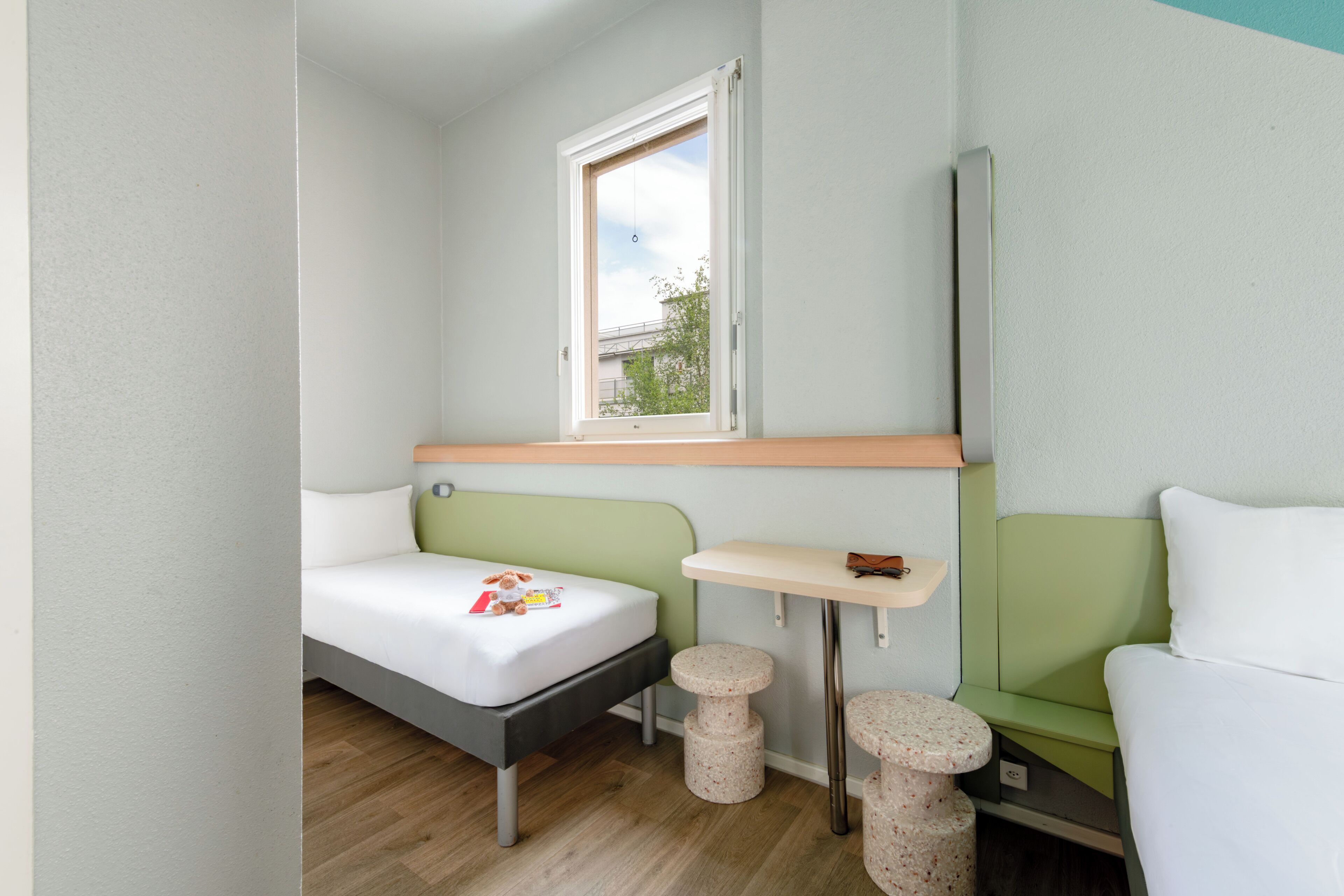 A compact room with a bed, a small table, and a window.
