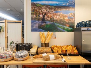 Un bufé de desayuno con panes, quesos y untables varios.