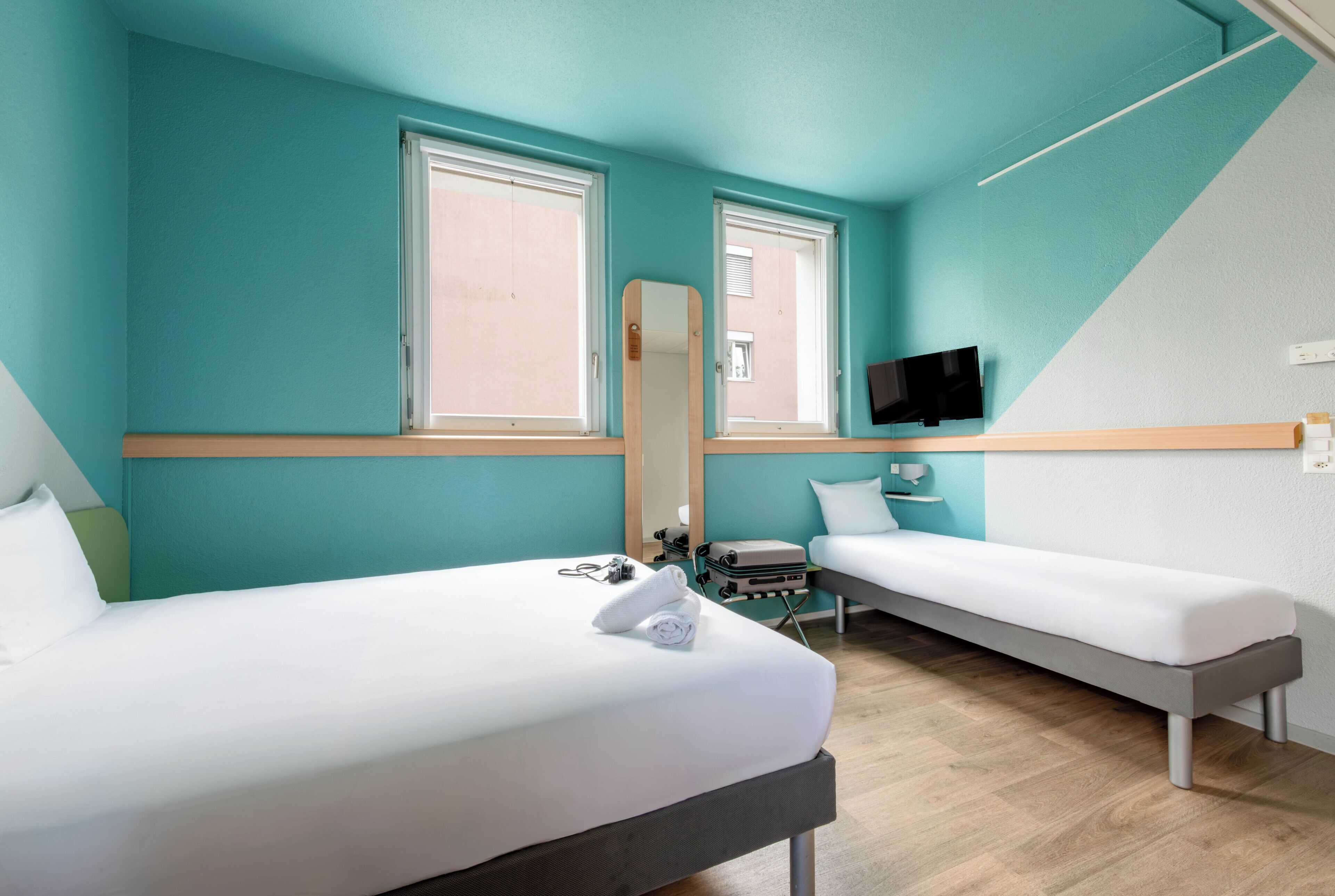 Habitación de hotel con dos camas, un televisor de pantalla plana y una ventana.
