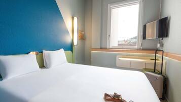 Une chambre d’hôtel avec un lit, une fenêtre, une télévision et une valise.