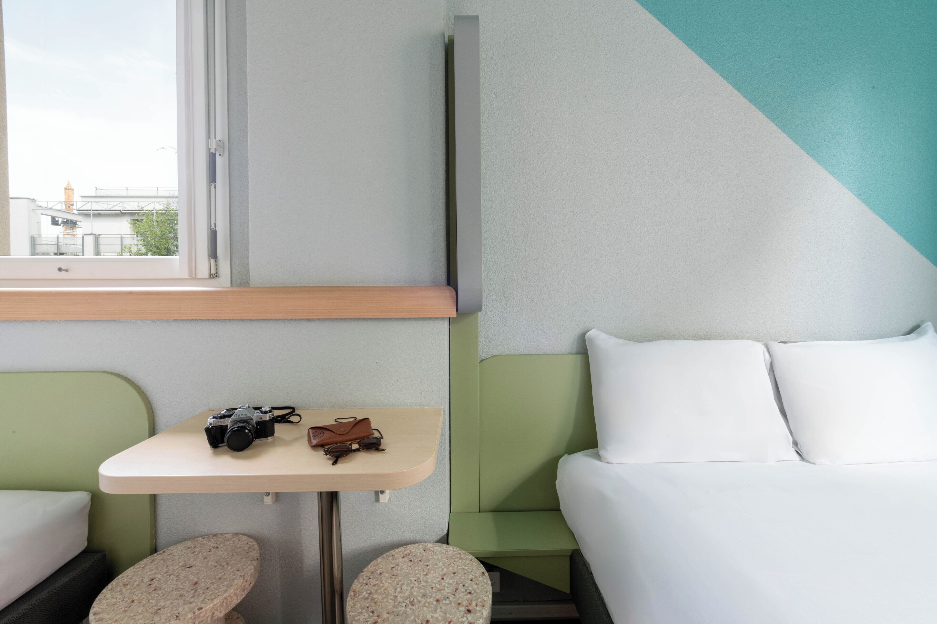 Une chambre d’hôtel avec un lit, une petite table et une fenêtre.