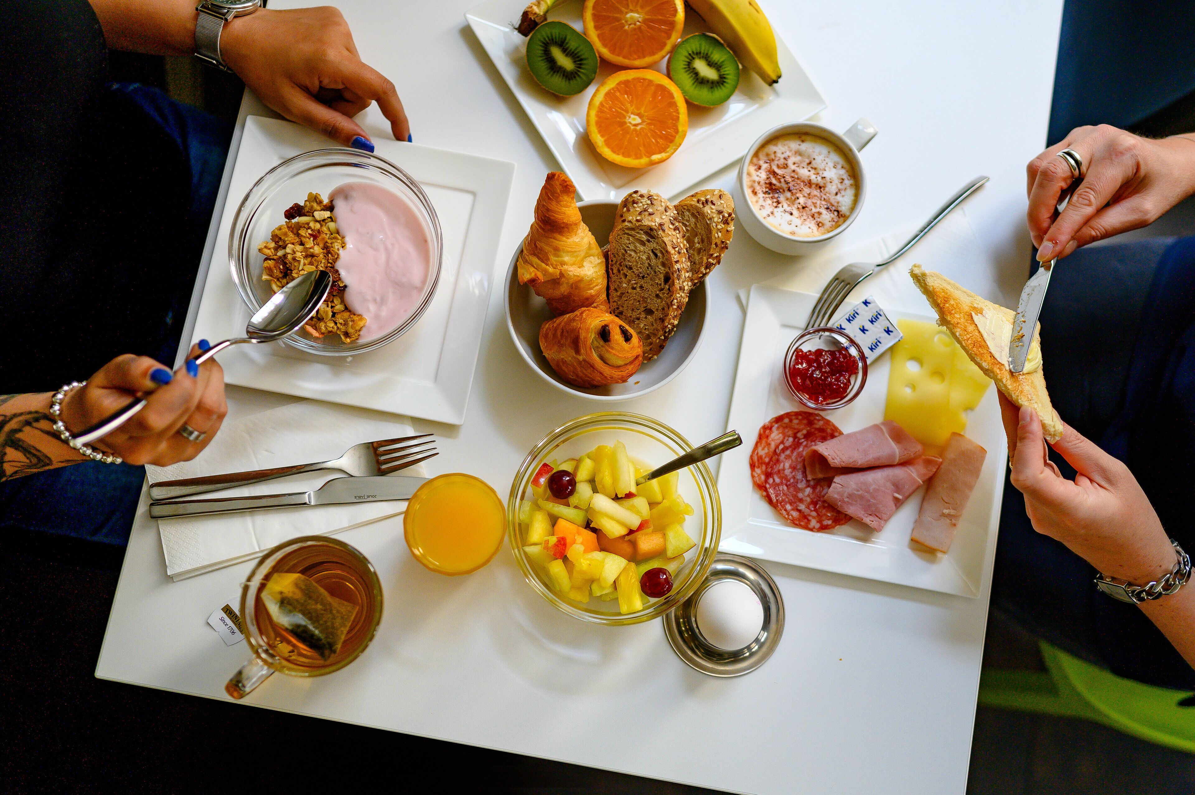A breakfast setting with various food items and utensils on a table.