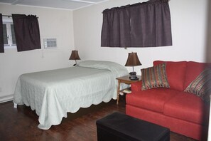 A room with a bed, a red sofa, two lamps, and a small table. - Green Haven Resort (Lake George)