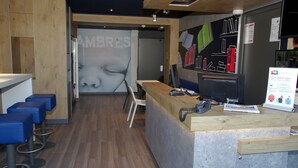 Un interior moderno con una recepción, taburetes de bar y una pared con un mural de un rostro grande.