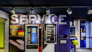 Quiosco de servicios con máquina expendedora y mostrador de autoservicio, que incluye un letrero destacado que dice 'SERVICE'.