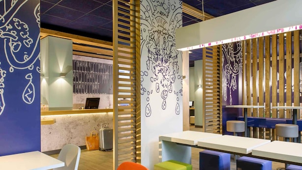 Un interior moderno con mesas blancas, sillas coloridas y decoración mural.