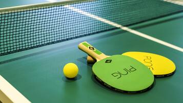 A table tennis table with a net, two paddles, and a ball.