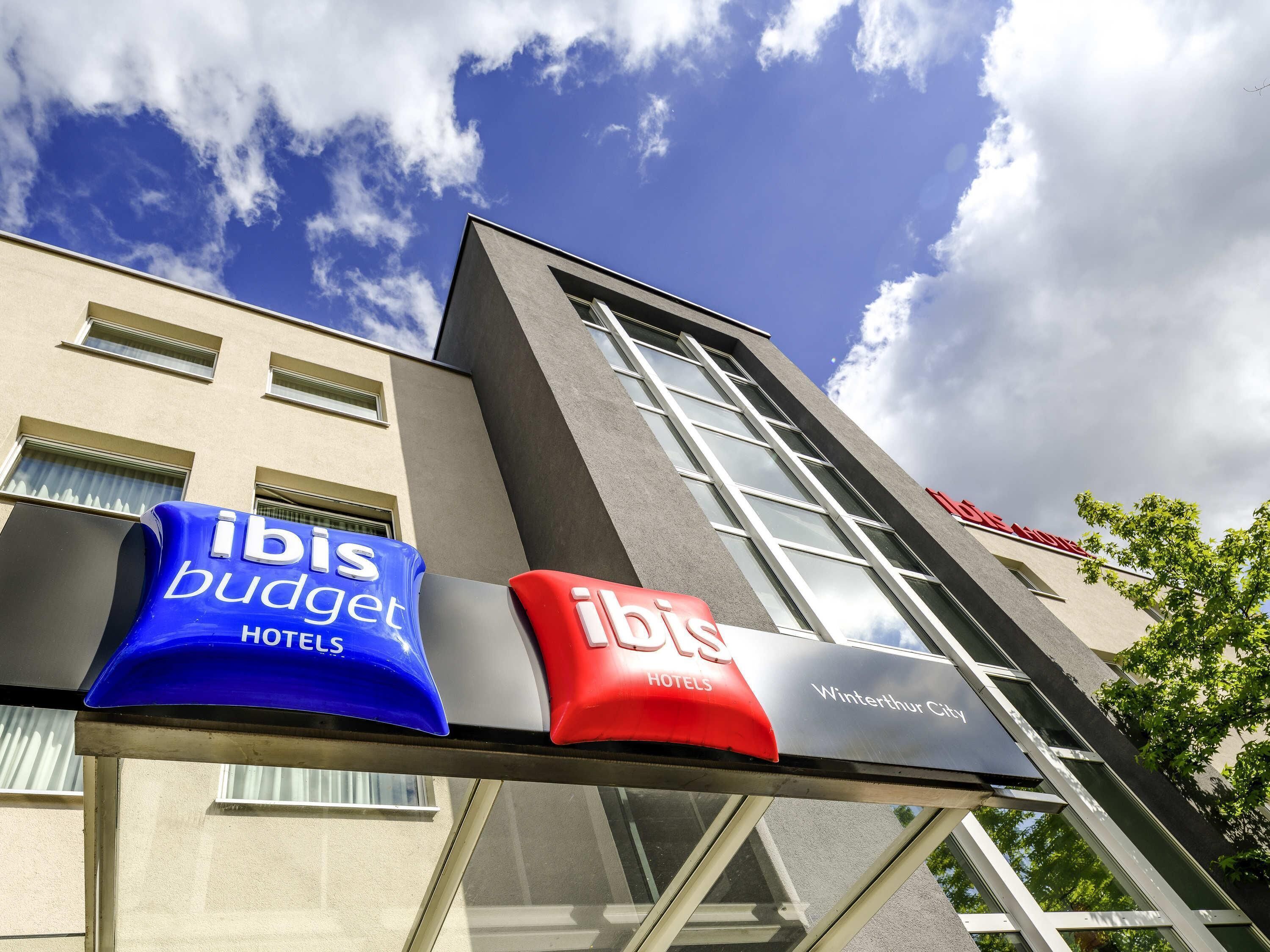 Un hotel amb una façana moderna, grans finestres i indicadors per a 'ibis budget hotels' i 'Winterthur City'.