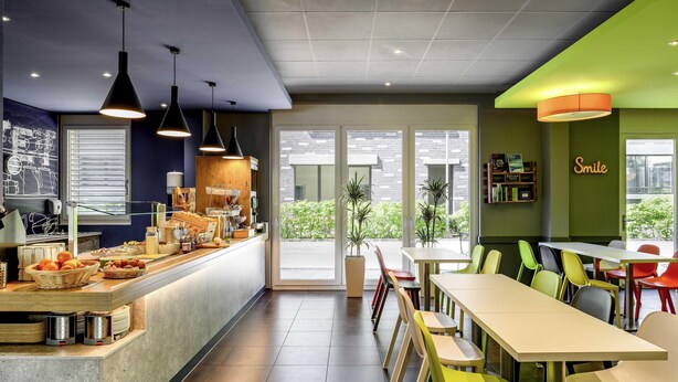 Una cafetería con mostrador, zona de estar y vistas al exterior.