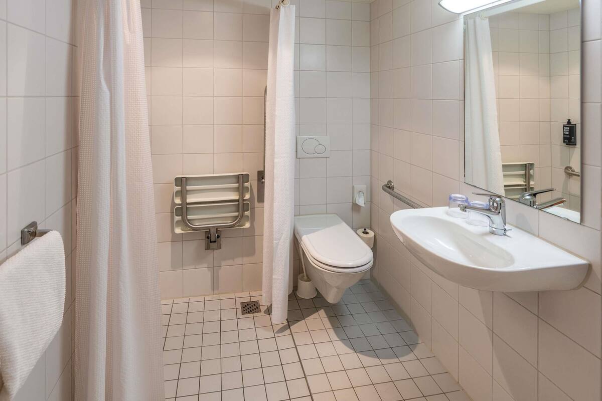 A bathroom with a toilet, sink, and shower curtain.