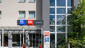 Una entrada de hotel moderna con puertas de cristal, un mostrador de recepción y señalización para "ibis budget hotels".